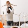 Dad carrying child over his head with windmill models in the forefront