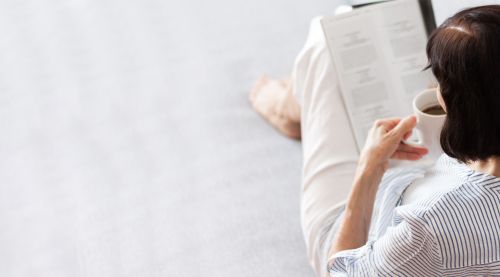 Woman reading magazine while drinking coffee