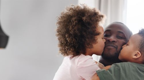children kissing father on cheek