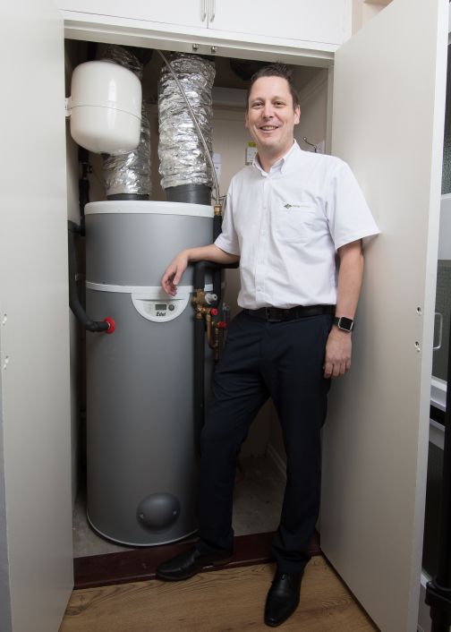 Dimplex Edel hot water heat pump in cupboard with man standing in front