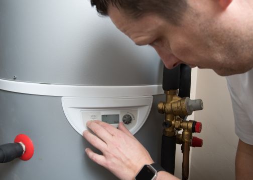 Dimplex Edel hot water heat pump with man adjusting digital controls