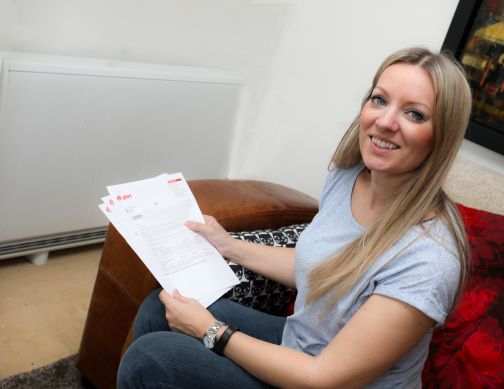 Woman smiling holding her energy bills beside Quantum heater from Dimplex
