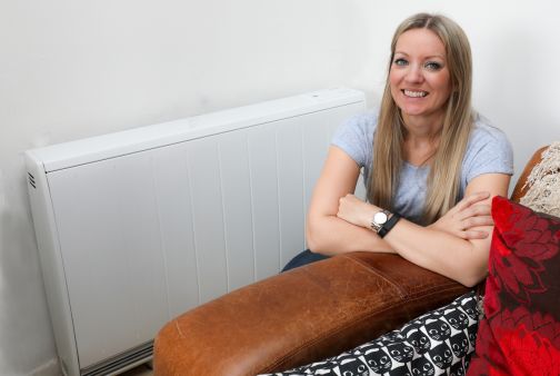 woman knelt smiling beside dimplex quantum storage heater