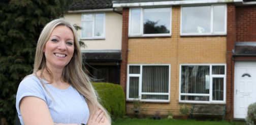 Woman standing smiling outside her house