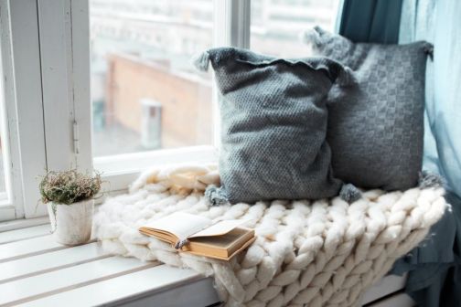 open book on window ledge next to some cushions 