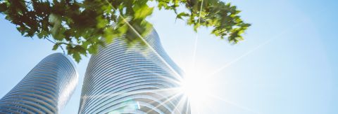 sun flare against tall building with glass windows