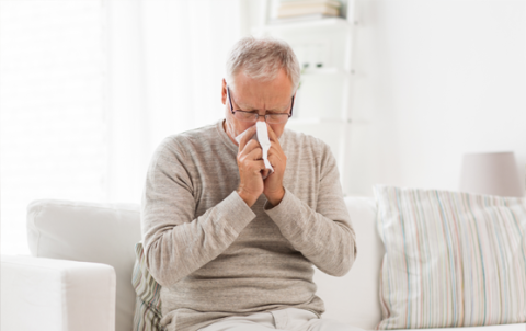 man sitting on couch and sneezing