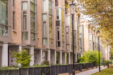 street view of apartment block with streetlamps and trees