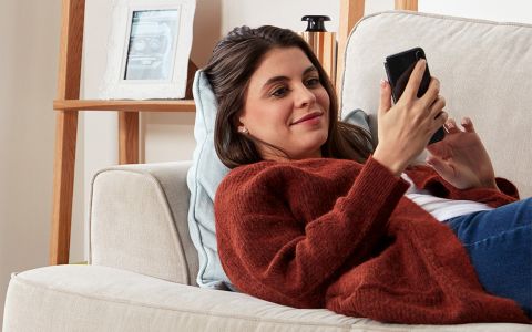 woman lying on couch looking at phone screen