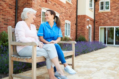 nurse talking to older woman on a bench