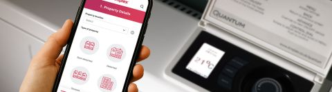 Hand holding mobile phone with heater in the background