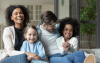 Glückliche Familie auf Sofa mit zwei Kindern lachend